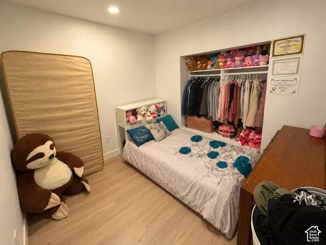 Recessed closet area with hanging rod, built-in shelving, and light wood-finish flooring