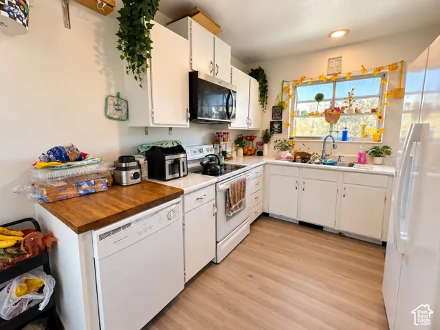 Bright kitchen featuring white cabinetry, wood-finish countertops, and stainless steel appliances including a gas range and microwave