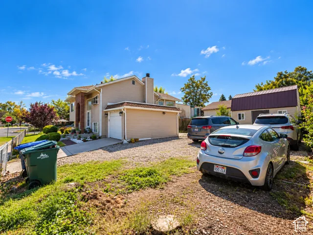 Two-story residence featuring a brick facade accent, attached garage, and gravel driveway