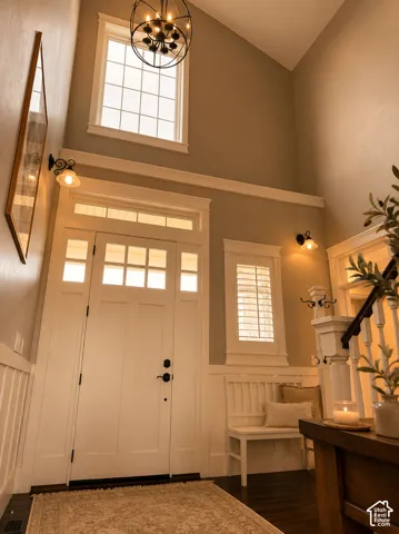 Vaulted ceiling, transom windows, built-in window seat, dark wood-finish flooring, and a decorative chandelier