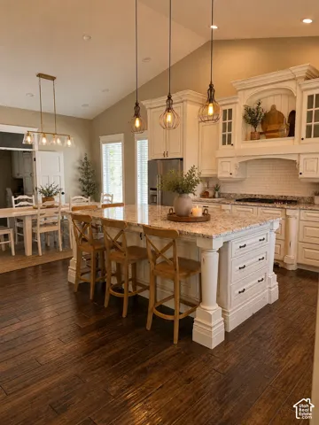 Kitchen featuring a large island with seating, white shaker-style cabinetry, granite countertops, and wood-finish flooring