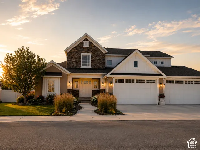 Stone and siding exterior with a multi-car garage, concrete driveway, and a manicured lawn