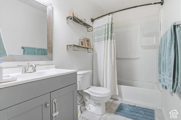 Bathroom featuring a vanity with gray cabinetry, a white countertop with an integrated sink, a framed mirror, and a tub/shower combination with a white surround