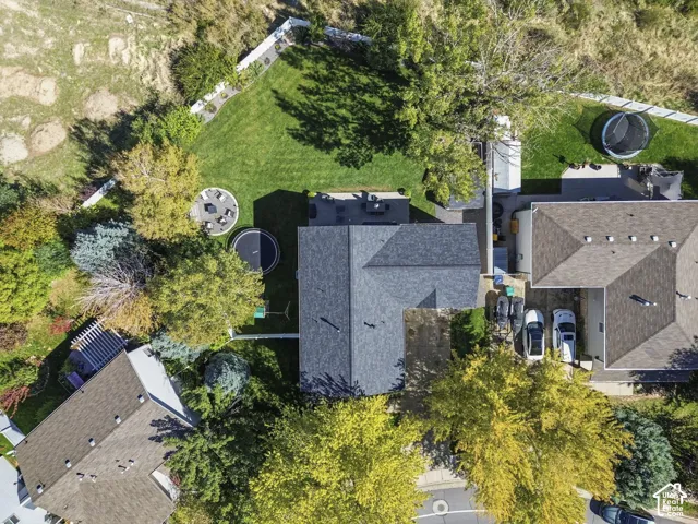 Expansive backyard featuring a manicured lawn, established trees, a circular patio, and a privacy fence