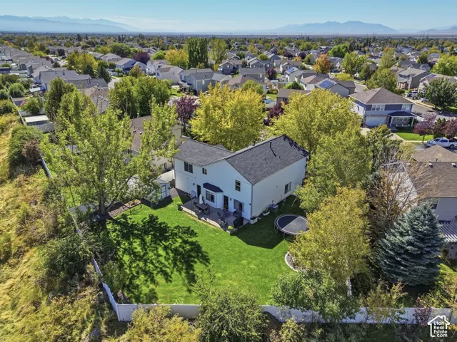 Expansive green lawn, mature trees, white privacy fencing, two-story exterior, and mountain backdrop