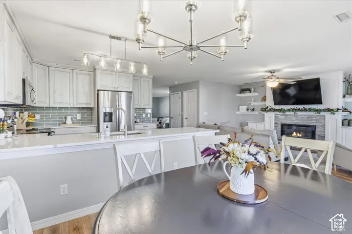Open concept room featuring a kitchen with light-toned cabinetry, stainless steel refrigerator, and subway tile backsplash