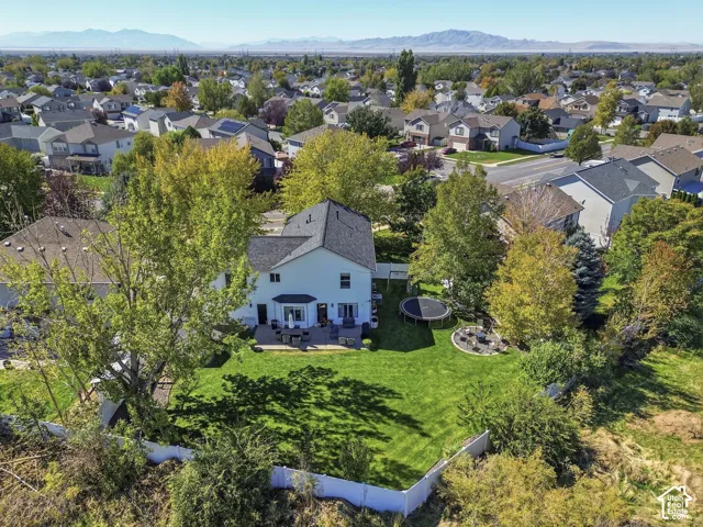 Expansive backyard featuring a manicured lawn, established trees, and a spacious patio area