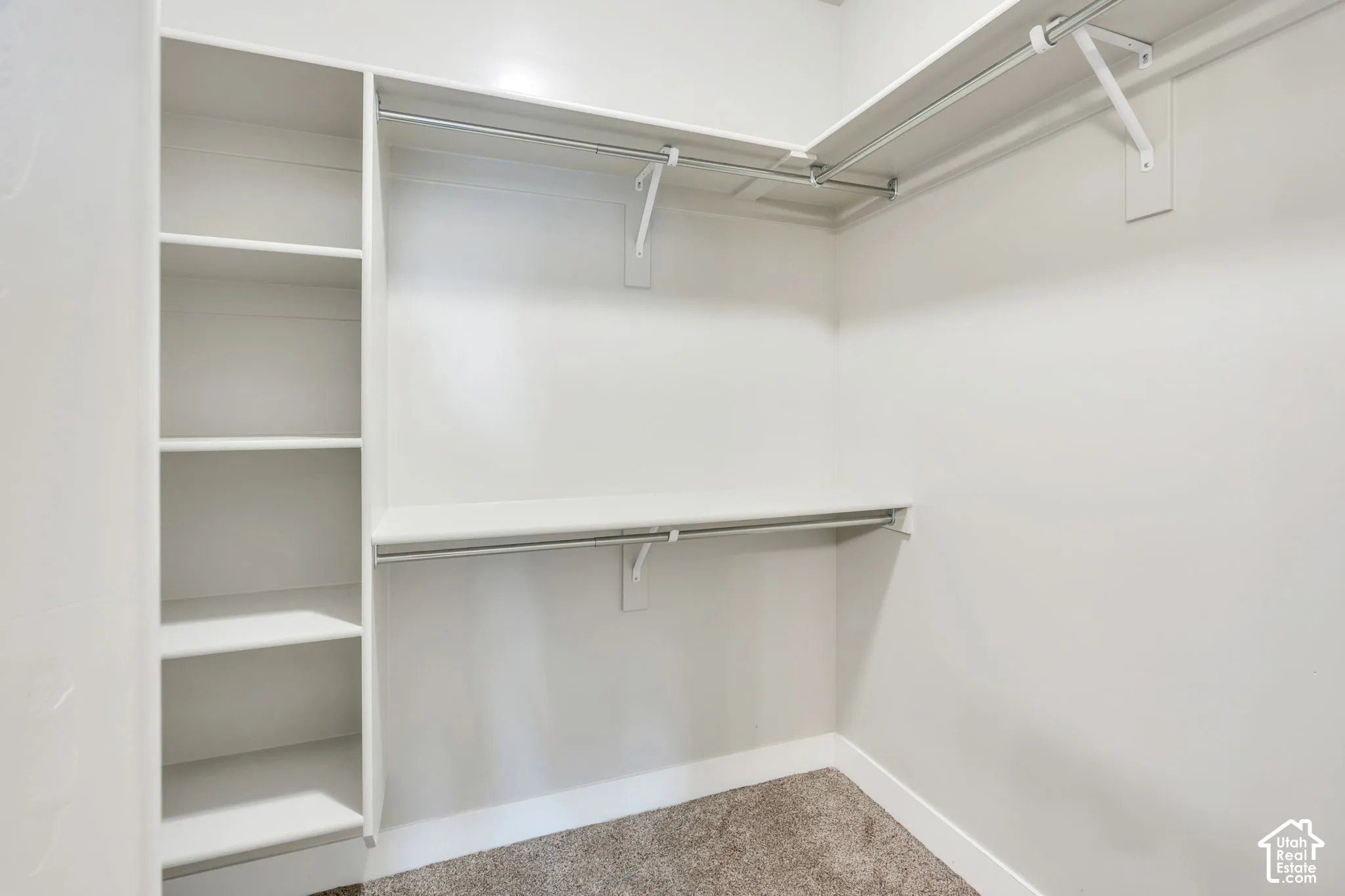Walk-in closet featuring built-in shelving, multiple hanging rods, and neutral-toned carpeting