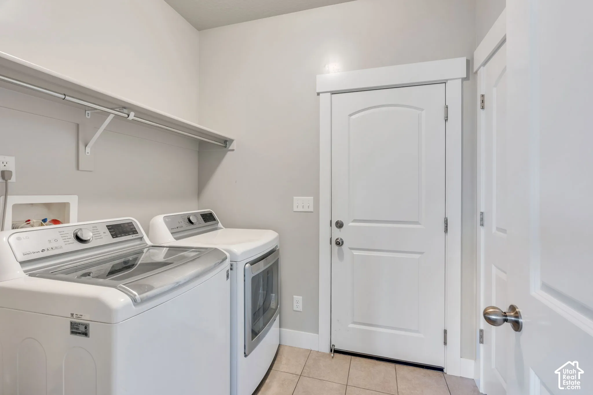 Laundry area featuring a built-in shelf with hanging rod, durable tile flooring, and multiple white paneled doors