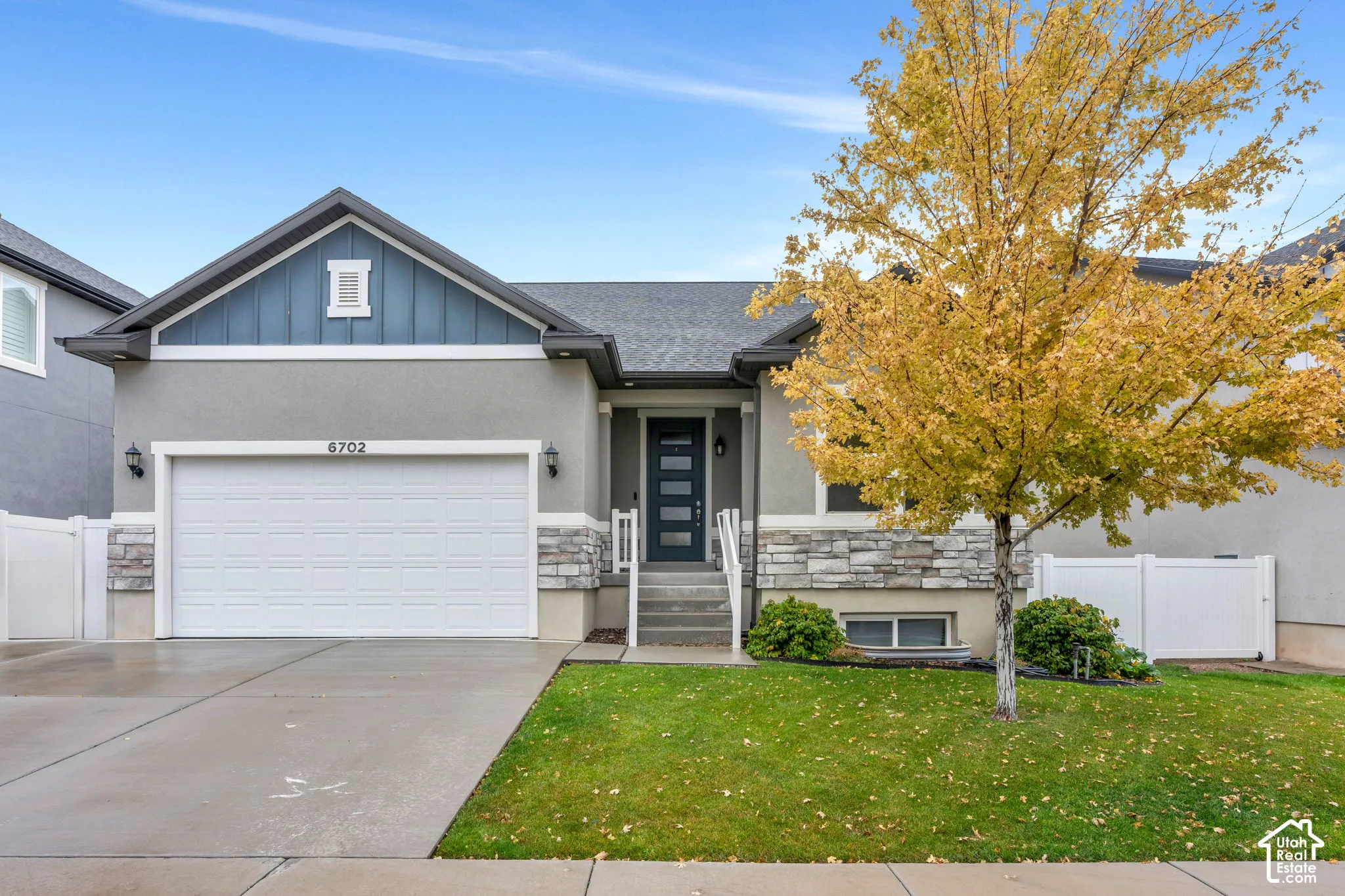 Stucco exterior with stone accent detailing, attached garage, and a covered entry