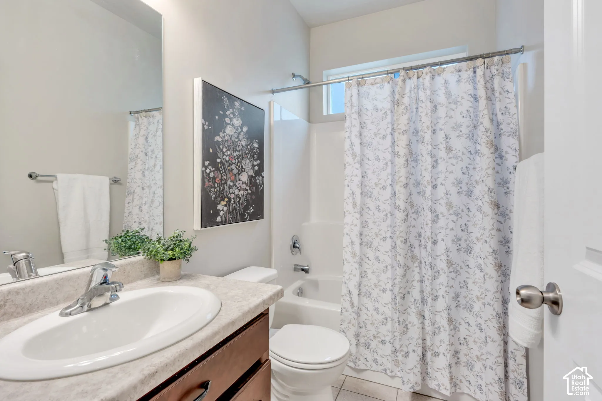 Bathroom featuring a single vanity with an integrated sink, a wood-finish cabinet, and a shower-tub combination with a window