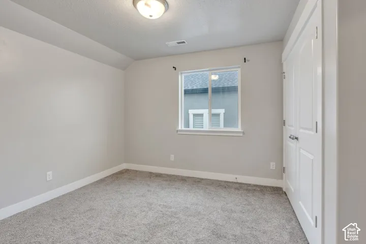 Carpeted room with a single window, white trim, and a flush-mount ceiling light