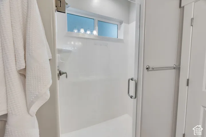 Glass-enclosed shower with a chrome handle, featuring a window and a wall-mounted shower fixture