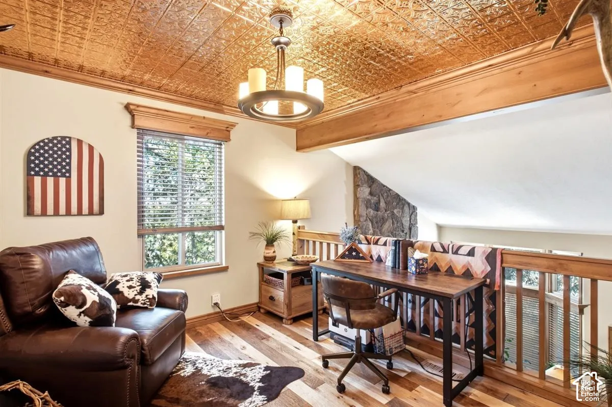 Wood-finish flooring with a decorative ceiling, exposed wood beams, and a wood-framed window