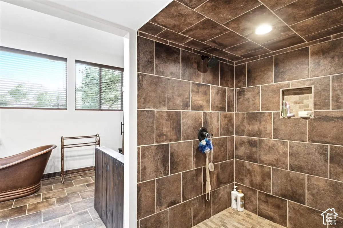 Spacious walk-in shower with brown tiled walls and recessed lighting