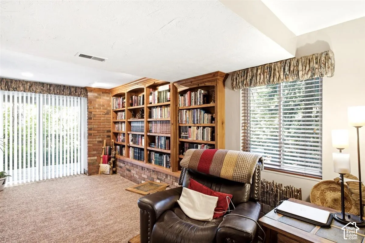 Built-in custom shelving, exposed brick wall accents, and carpet flooring
