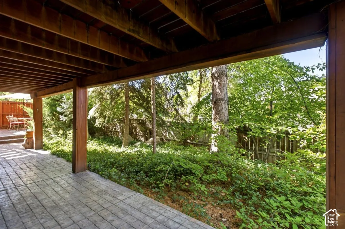 Covered patio with stamped concrete flooring, exposed wood beam ceiling, and wood support columns