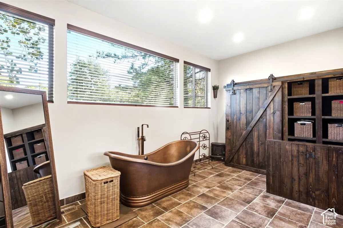 Large format tile flooring complements a freestanding soaking tub with a floor-mounted faucet