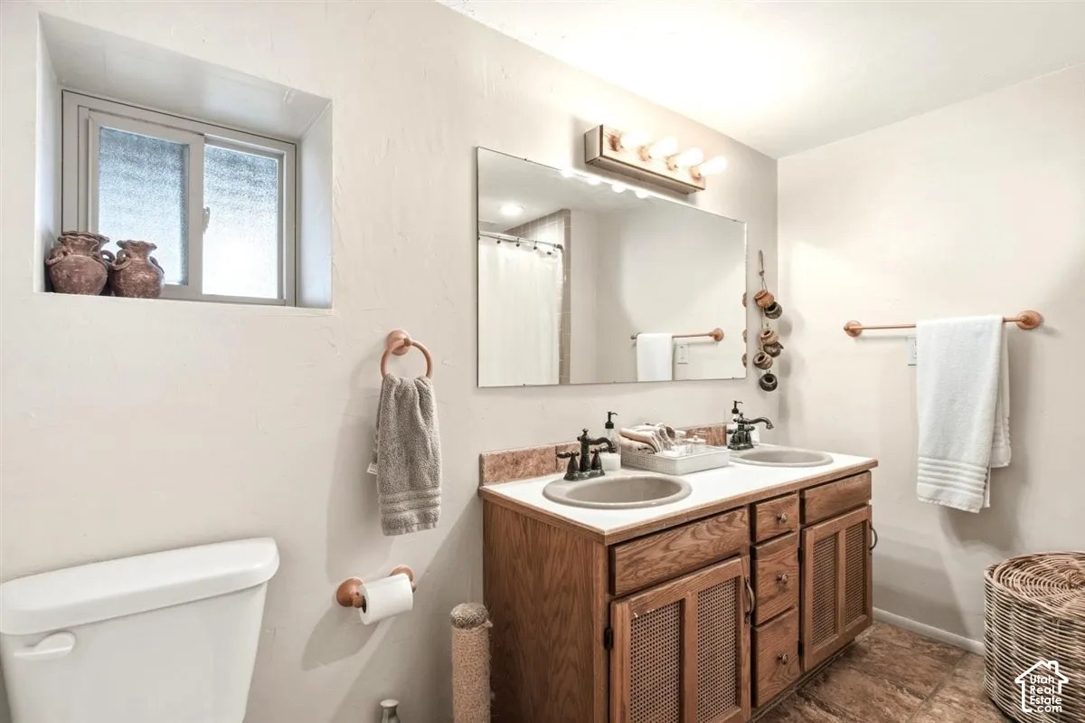 Dual vanity with wood-finish cabinetry and integrated sinks, complemented by a large wall mirror and overhead light fixture
