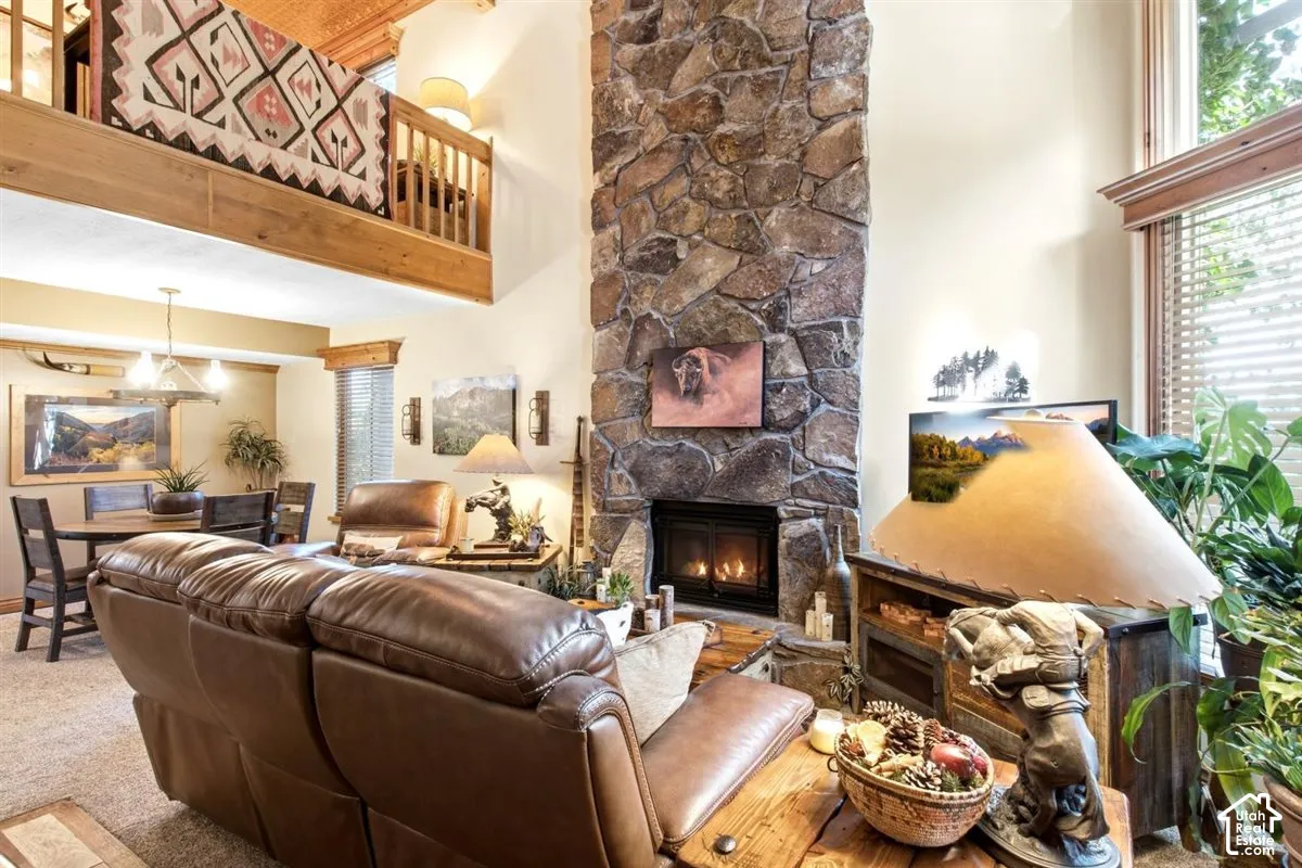 Soaring ceilings with wood-beam accents, stone-faced fireplace, and an upper-level balcony with wood railing