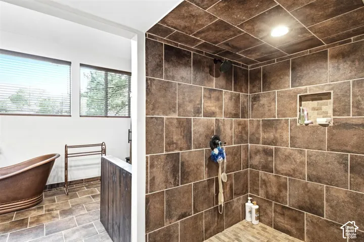 Spacious walk-in shower with brown tiled walls and recessed lighting