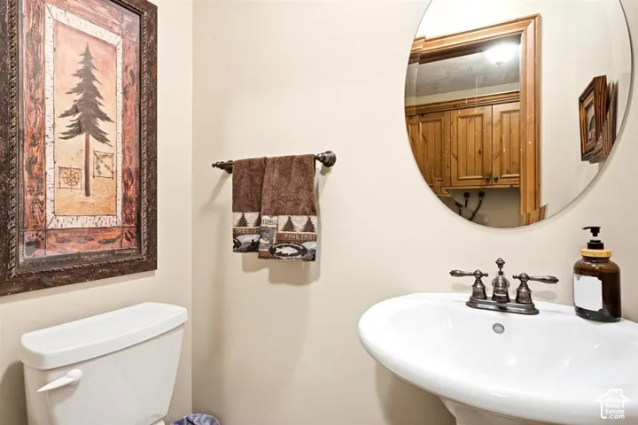 Pedestal sink with bronze-finish faucet, rounded mirror, and light-toned walls