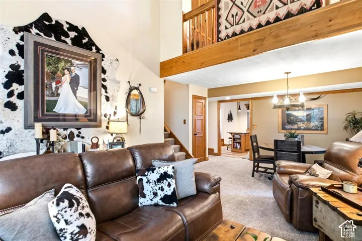 Vaulted ceiling with exposed wood beam, wood-finish interior doors and trim, carpeted flooring, and a dining area with a chandelier