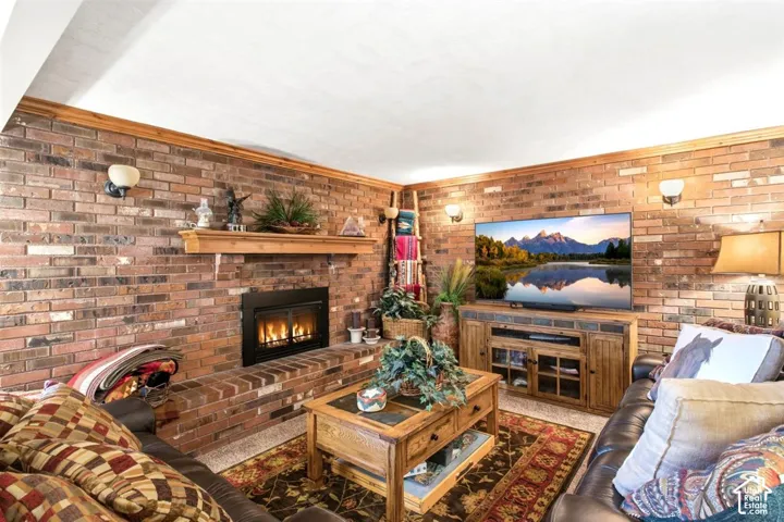 Brick-clad walls featuring sconce lighting, a built-in fireplace with a hearth, and a wood mantel