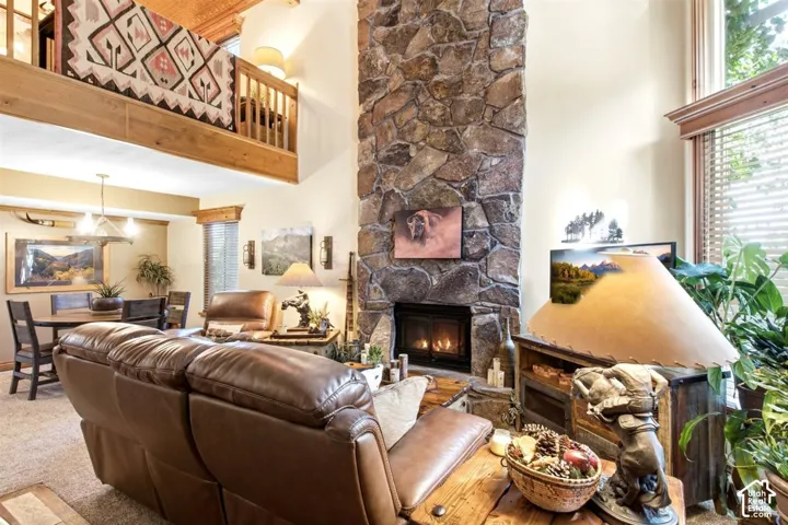 Soaring ceilings with wood-beam accents, stone-faced fireplace, and an upper-level balcony with wood railing