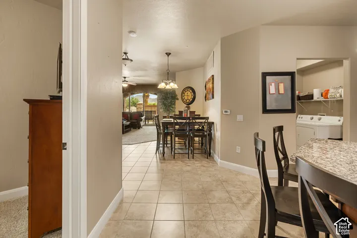 Tiled flooring extending into the dining area, ceiling fan, recessed lighting, and a dedicated laundry area with shelving