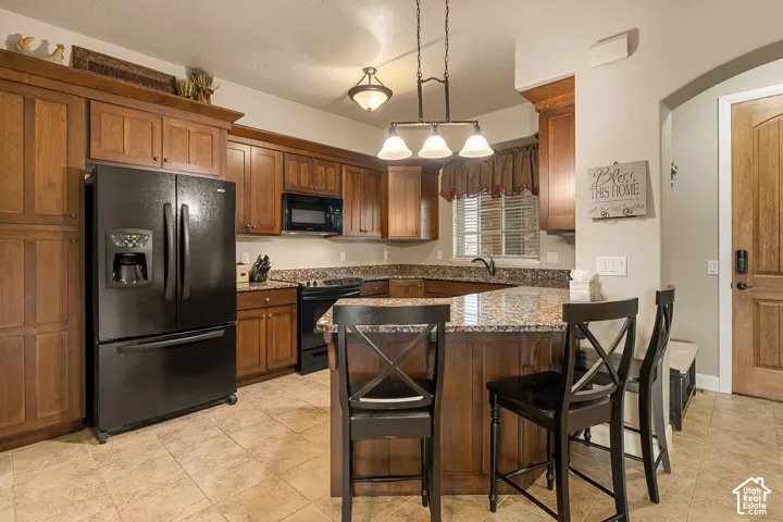 Wood-finish cabinetry, built-in black appliances, granite-style countertops, and tile flooring