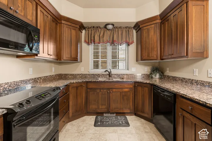 U-shaped kitchen featuring wood cabinetry, speckled countertops, stainless steel sink with a gooseneck faucet, black oven, and black microwave