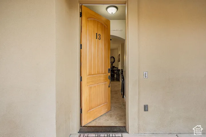 Natural wood-panel door with an arched top, tile flooring, and recessed ceiling lighting