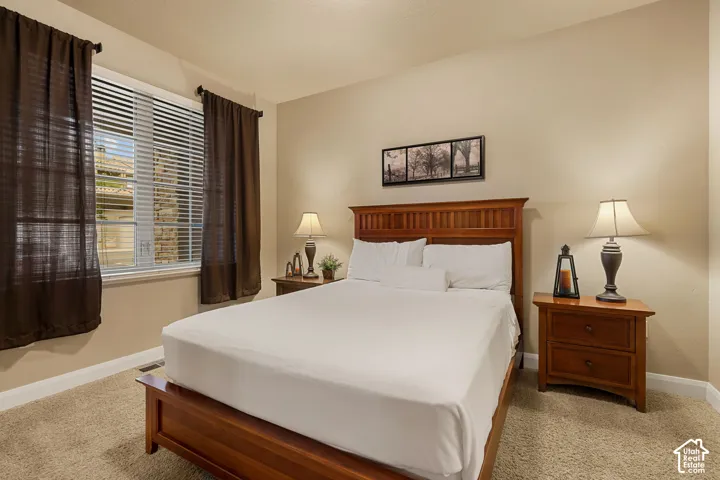 Neutral tone wall paint, carpet flooring, a window with blinds, and wood-finish trim