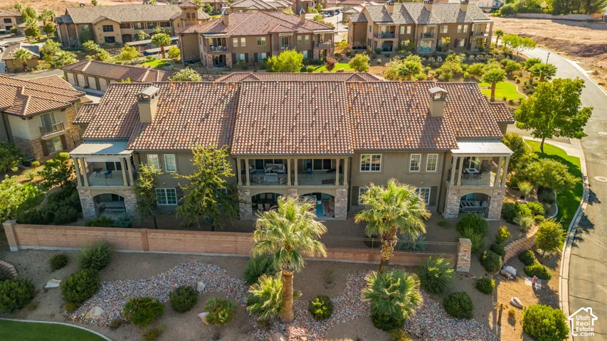 Terracotta tile roof, stucco exterior, multiple covered balconies, stone architectural elements, and mature palm trees