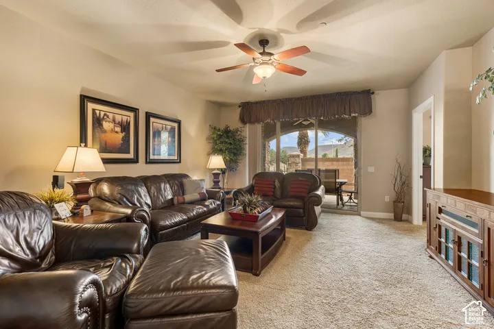 Arched patio door, ceiling fan with integrated lighting, neutral wall color, and light-toned carpeting