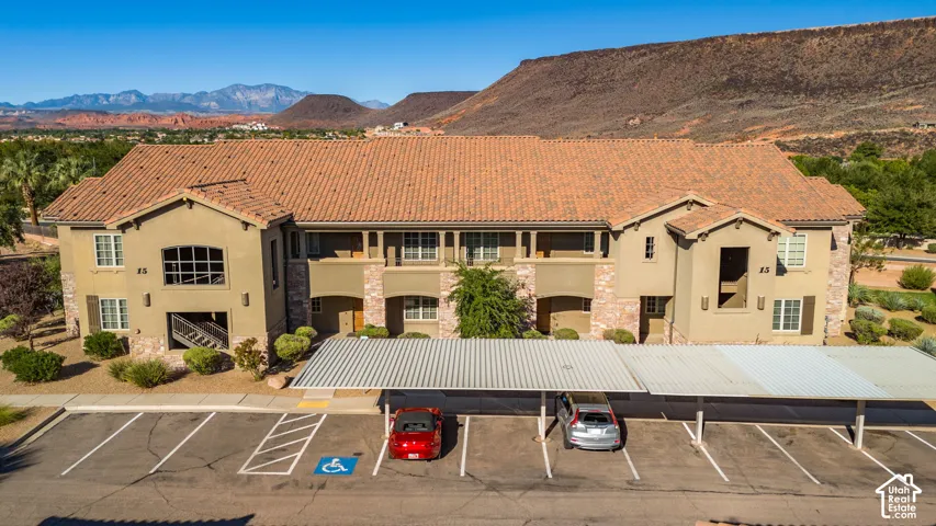 Multi-story stucco exterior featuring a tile roof, stone accents, multiple balconies, and a covered parking structure
