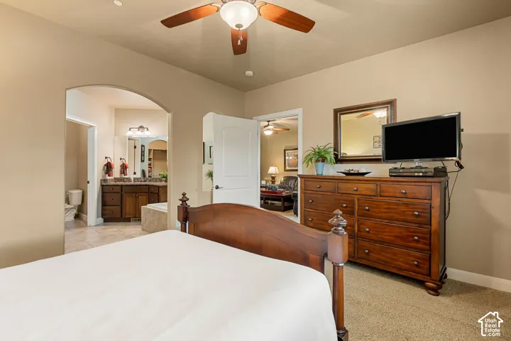 Arched entryway to bathroom with dual vanity and built-in tub