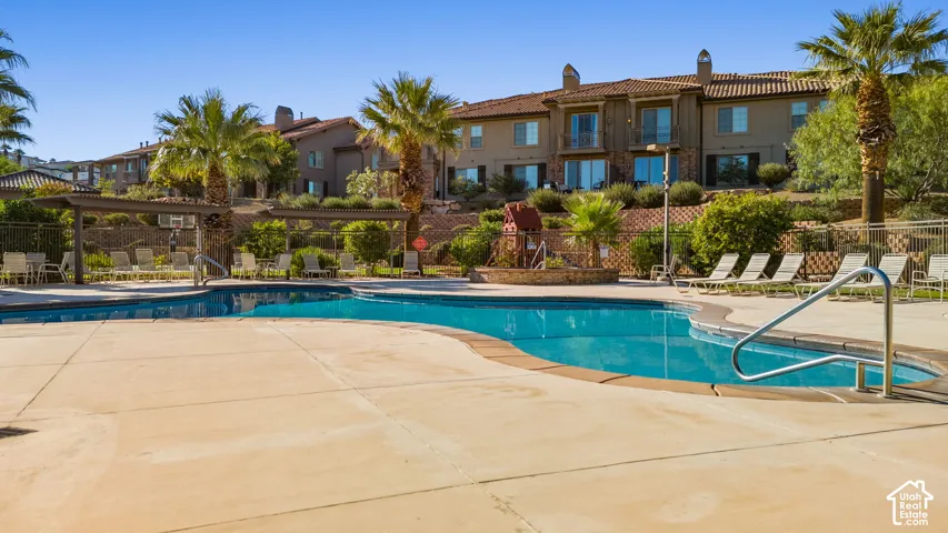 Resort-style pool area with integrated spa, surrounding concrete decking, and pergola-covered seating