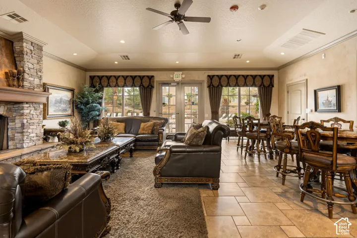 Stone-clad fireplace, recessed lighting, ceiling fan, tile flooring, and multiple glass French doors