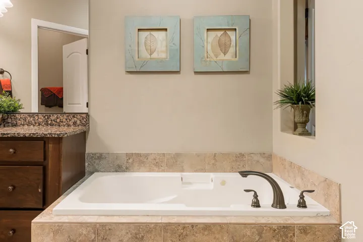 Built-in bathtub with a bronze-finish faucet, surrounded by tiled decking and a tiled wainscot