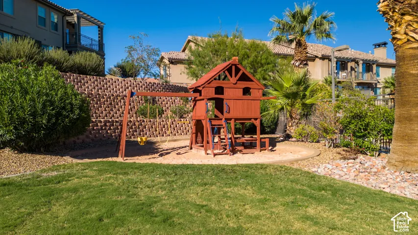 Manicured lawn area with a built-in play structure featuring a swing set and sandbox