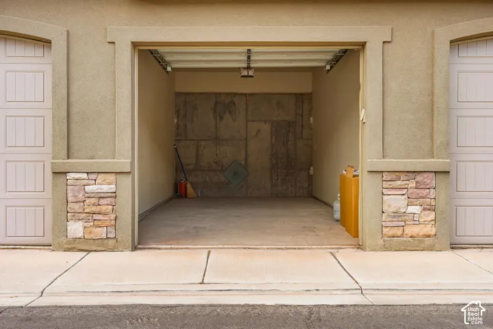 Attached garage space featuring concrete flooring, textured stucco exterior, and decorative stone accents