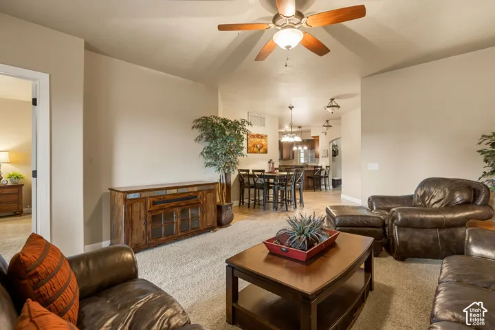 Vaulted ceiling with a ceiling fan, carpeted flooring, and a wood-finish media console