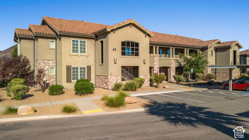 Multi-level building with a tile roof, stucco exterior, stone accents, and covered parking