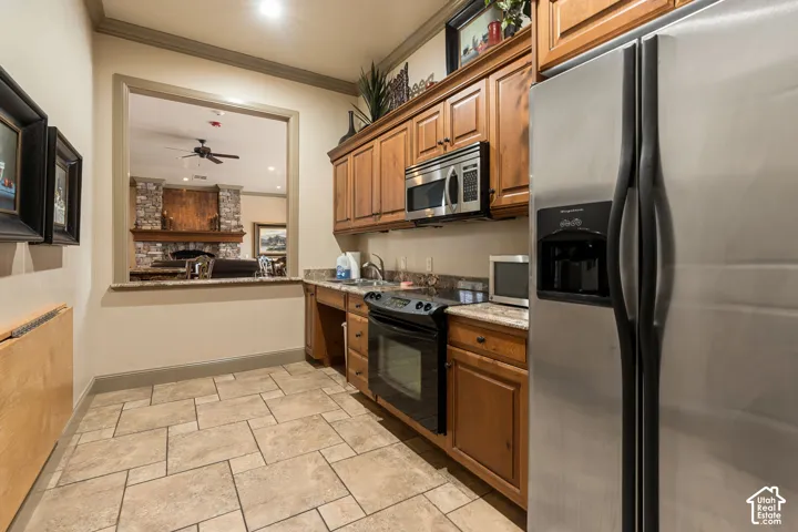 Kitchenette featuring stainless steel appliances, wood cabinetry, stone countertops, and tile flooring