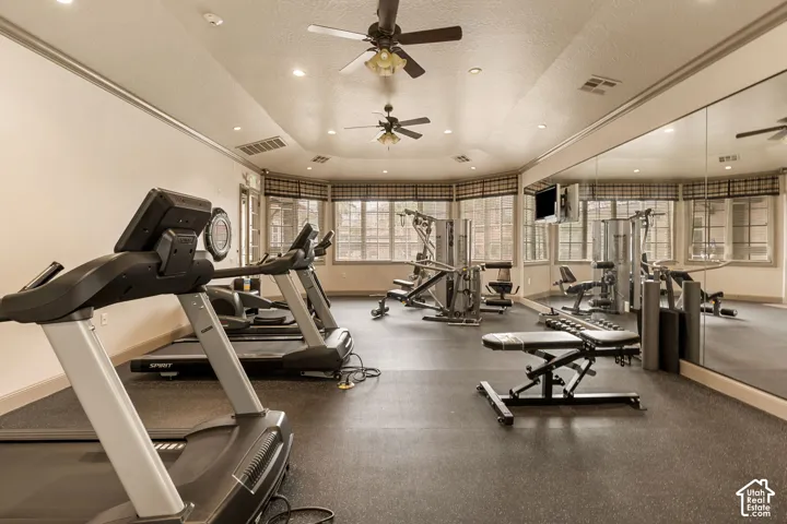 Fitness room with rubber flooring, recessed lighting, multiple ceiling fans, and full-wall mirrors