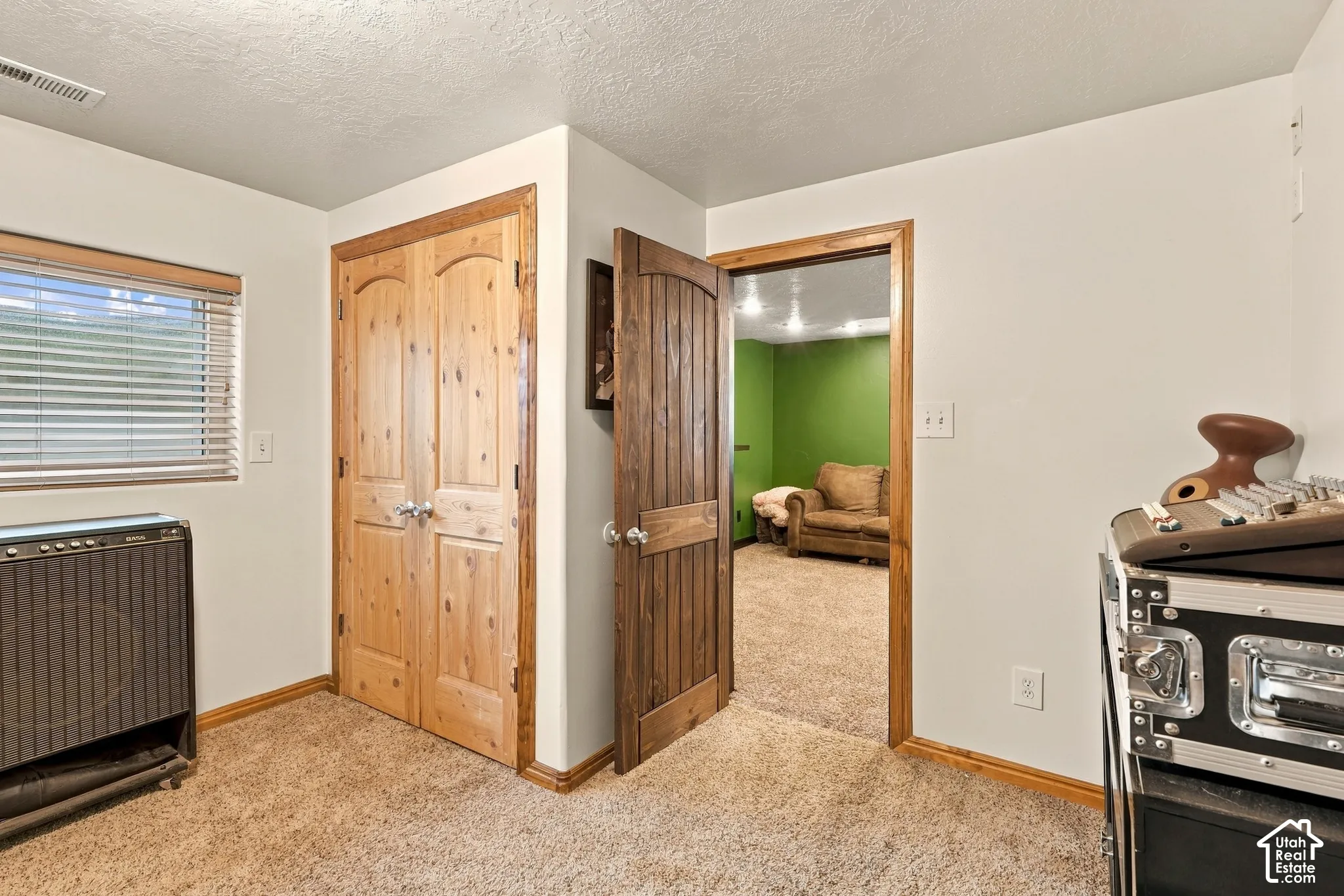 Carpeted room with wood-finish trim, a window with blinds, and a wood-finish bi-fold closet door