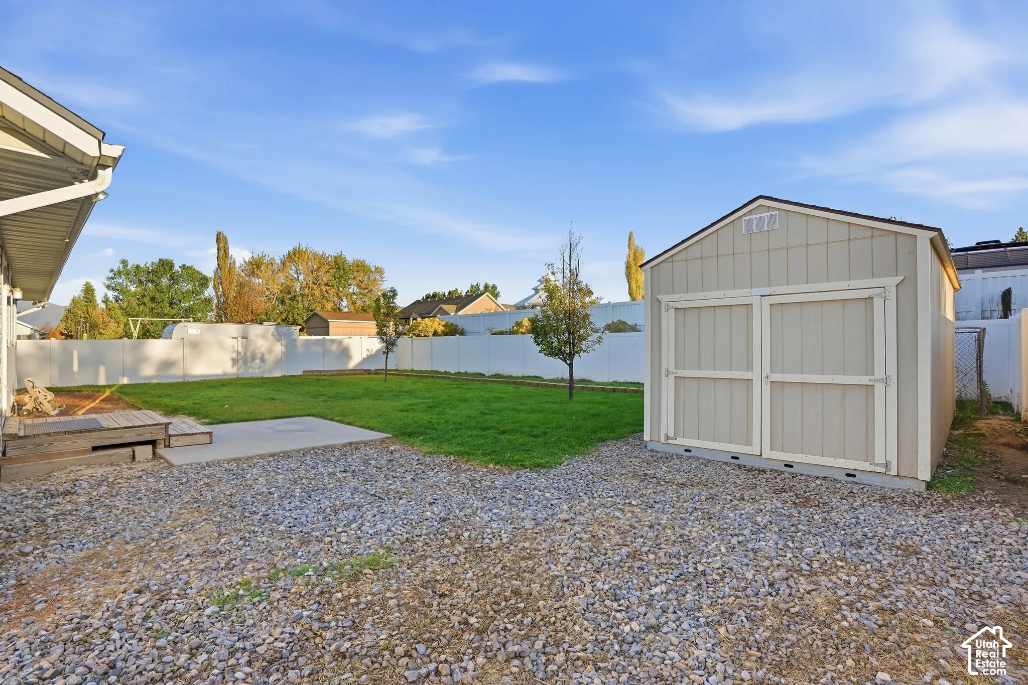 Expansive backyard featuring a gravel area, concrete patio, and a separate storage shed with a gable roof