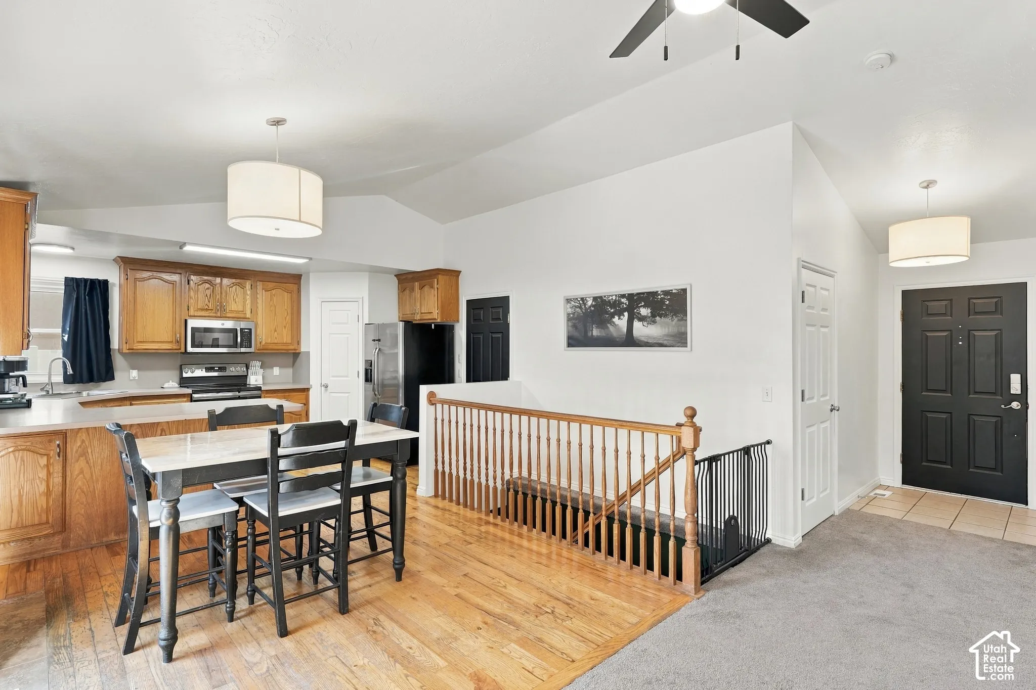 Wood-finish flooring, wood cabinetry, stainless steel appliances, breakfast bar, and wood stair railing
